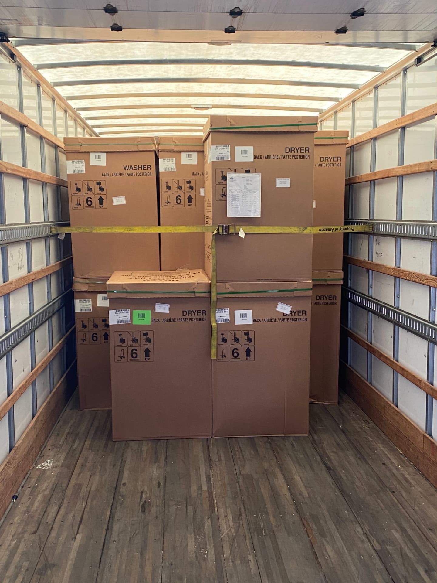 A real box-truck load of washers and dryers secured with cargo straps